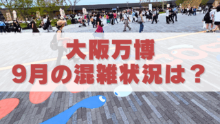大阪万博の会場で多くの来場者が歩く広場の様子。地面にはカラフルなキャラクター風の装飾が描かれており、中央に「大阪万博 9月の混雑状況は？」と大きく書かれたテキストが重ねられている。